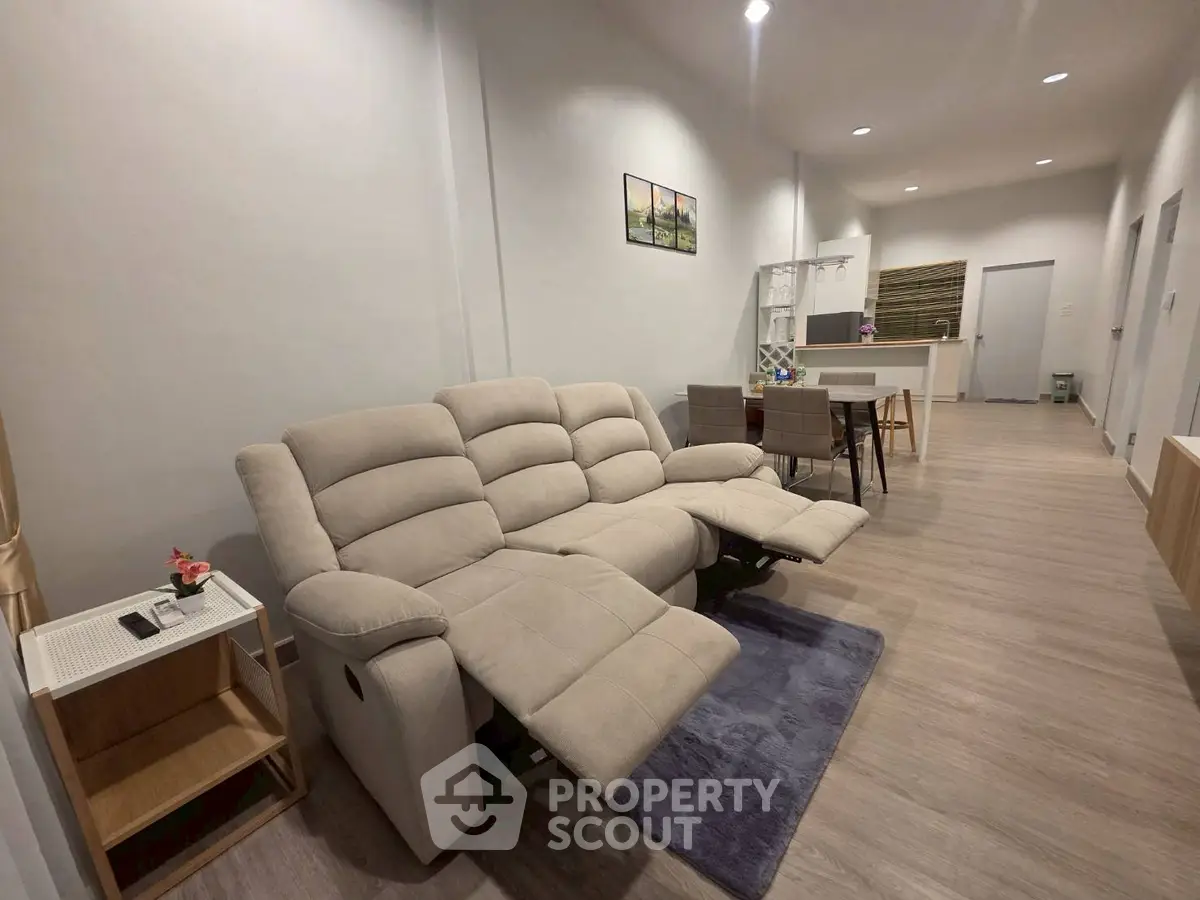 Spacious living room with modern recliner sofa and open layout dining area
