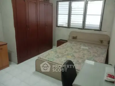 Cozy bedroom with wooden wardrobe and large window, ideal for comfortable living.