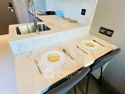 Modern kitchen with marble countertop and stylish dining setup in a contemporary apartment.