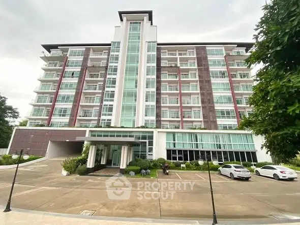 Modern multi-story residential building with spacious parking area and lush greenery.