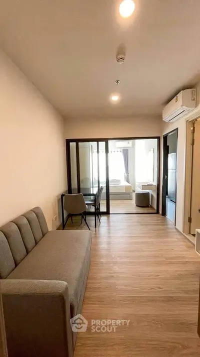Modern apartment interior with open layout, featuring a cozy living area and glass partitioned bedroom.