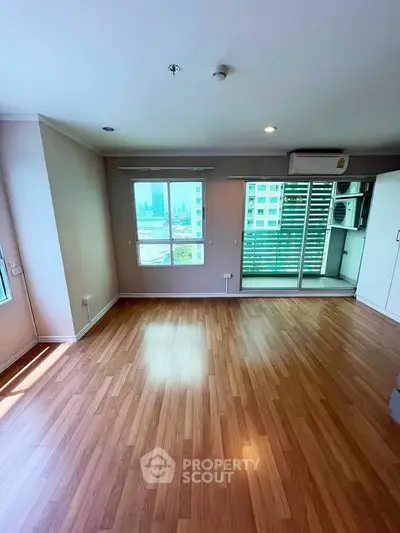 Spacious living room with wooden flooring and balcony access in modern apartment.