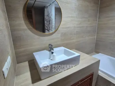 Modern bathroom with stylish sink and mirror, featuring elegant wood paneling.