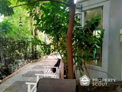 Charming garden pathway beside a modern home with lush greenery and cozy seating area.