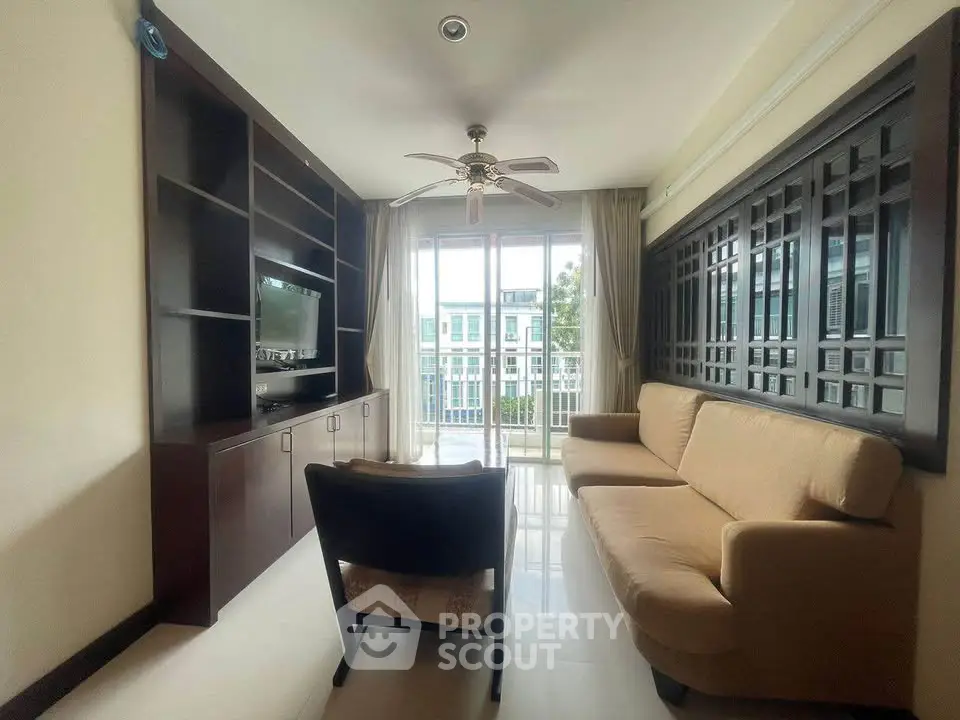 Cozy living room with modern furniture and large window offering natural light and a view.
