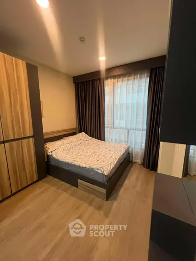 Modern bedroom with stylish wooden furniture and large window for natural light.