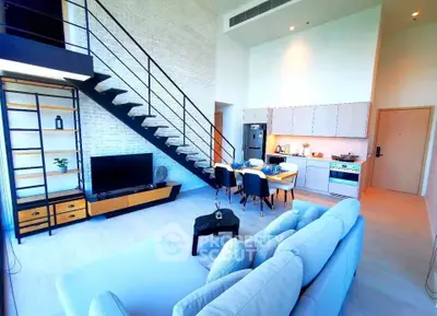 Modern loft apartment with open kitchen and stylish living area, featuring a sleek staircase and ample natural light.