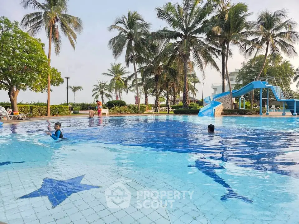 Luxurious outdoor pool with slide and palm trees in a tropical resort setting.