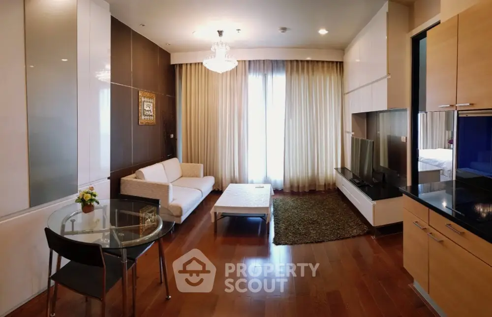 Elegant living room with modern decor and chandelier, featuring hardwood floors and cozy seating area.