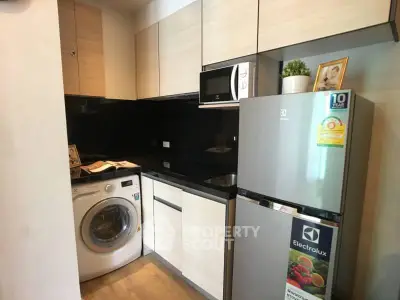 Modern kitchen with washing machine and Electrolux fridge in compact layout