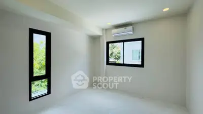 Bright and airy room with large windows and modern air conditioning unit, perfect for a cozy living space.