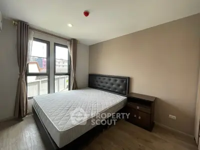 Modern bedroom with large window and stylish furniture in a cozy apartment.