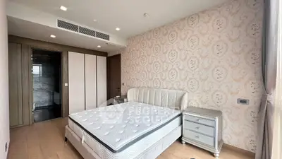 Luxurious bedroom with elegant wallpaper and modern furnishings in a high-end apartment.
