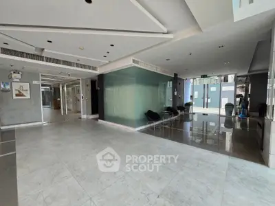 Spacious modern building entrance with sleek marble flooring and glass walls, ideal for luxury real estate.