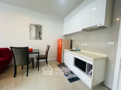 Modern kitchen with sleek cabinets, dining area, and vibrant red fridge for stylish living.