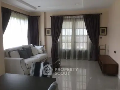 Elegant living room with large windows and stylish curtains, featuring a cozy sofa and modern decor.
