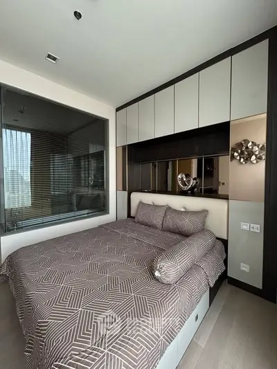 Modern bedroom with stylish decor and built-in storage, featuring a cozy bed and elegant wall art.