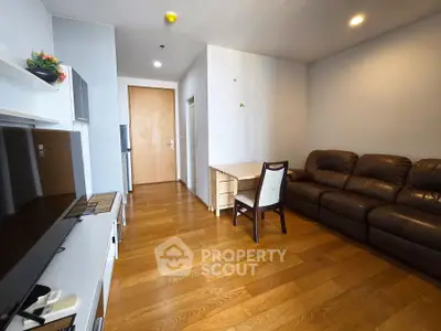 Modern living room with wooden flooring, leather sofa, and sleek TV unit in a cozy apartment.