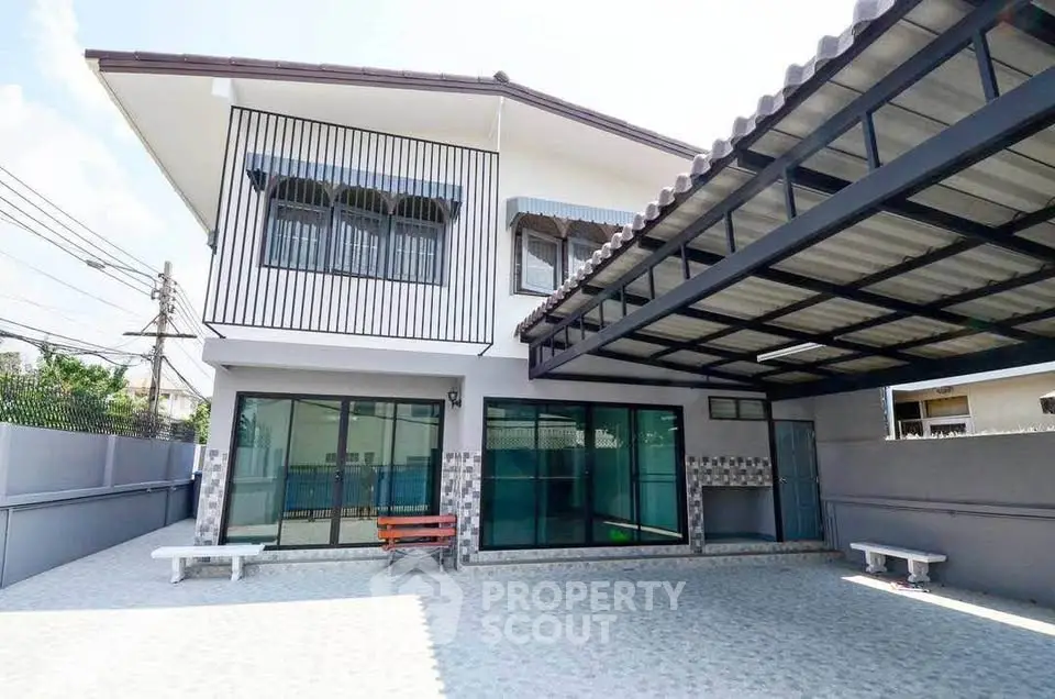 Spacious modern two-story house with large covered parking area and stylish exterior design.