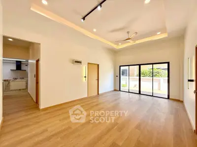 Spacious modern living room with wooden flooring and large windows offering natural light.