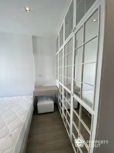 Modern minimalist bedroom with a large white bed, sleek built-in shelving units, and a cozy ambiance, perfect for urban living.