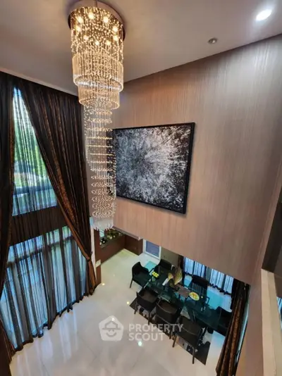 Luxurious double-height living room with elegant chandelier and modern dining area.