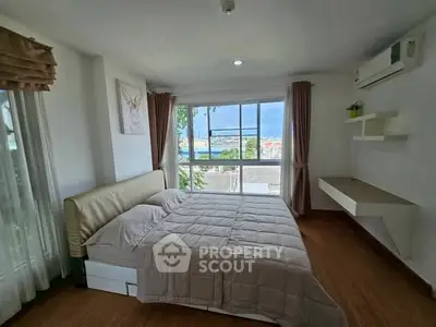 Bright bedroom with large window and modern decor, offering a cozy and inviting atmosphere.