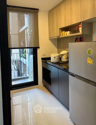 Modern kitchen with sleek cabinets and appliances, featuring a large window for natural light.