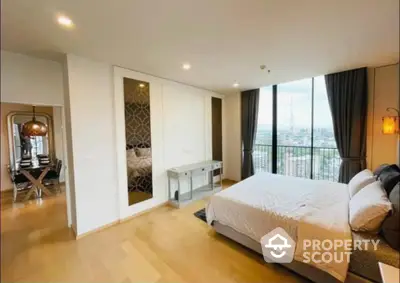 Spacious bedroom with large windows offering ample natural light, hardwood flooring, and modern furnishings, leading to a cozy balcony with a view.