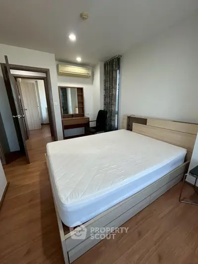 Modern bedroom with wooden flooring and minimalist furniture in a cozy apartment.