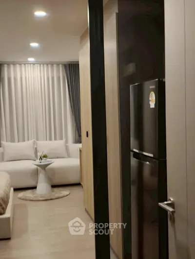 Modern living room with cozy sofa and sleek refrigerator in stylish apartment.