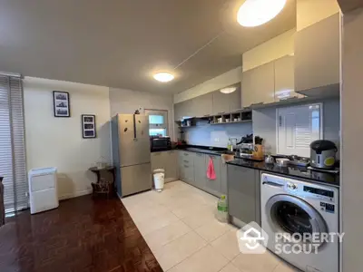 Modern kitchen with washing machine and stainless steel appliances in open layout design.