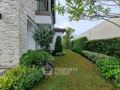 Beautifully landscaped garden with lush greenery and modern stone facade in a residential property.