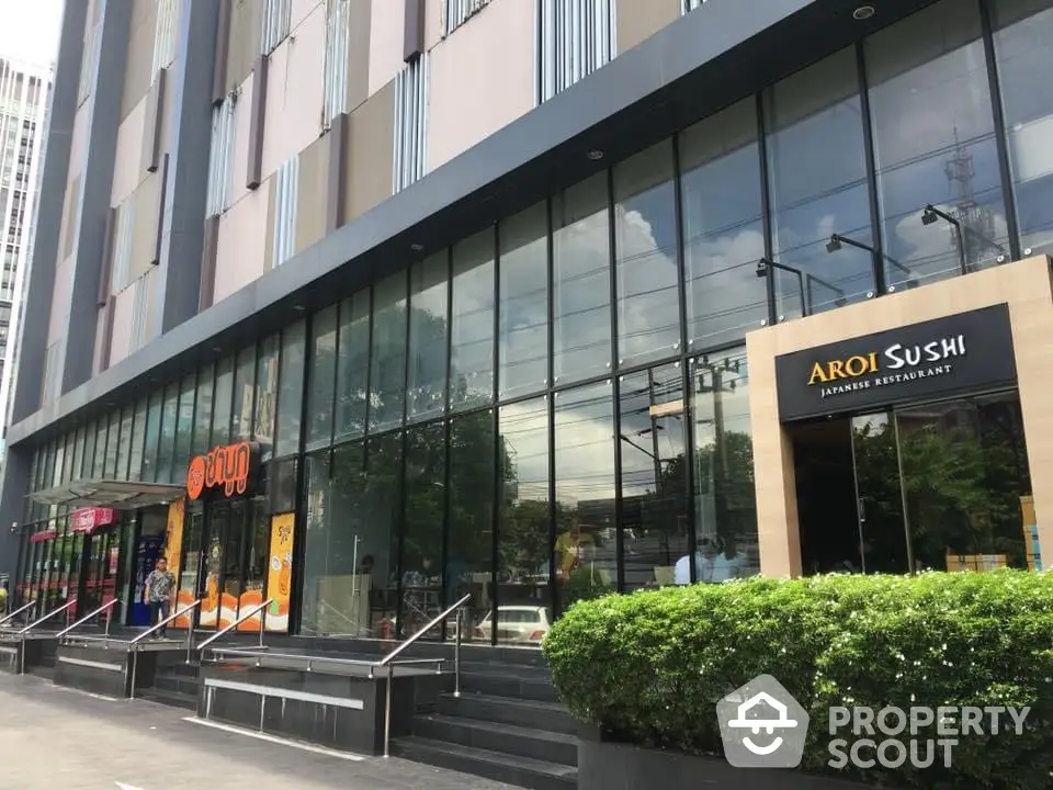 Modern commercial building exterior with glass facade and restaurant signage