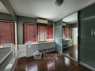 Spacious room with wooden flooring and large mirrored wardrobe, perfect for modern living.