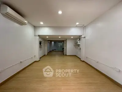 Spacious open-plan interior with wooden flooring and modern lighting, ideal for versatile use.