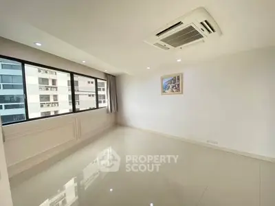 Spacious and bright living room with large windows and modern air conditioning unit.