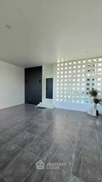 Spacious modern living room with stylish tile flooring and unique wall design, perfect for contemporary living.