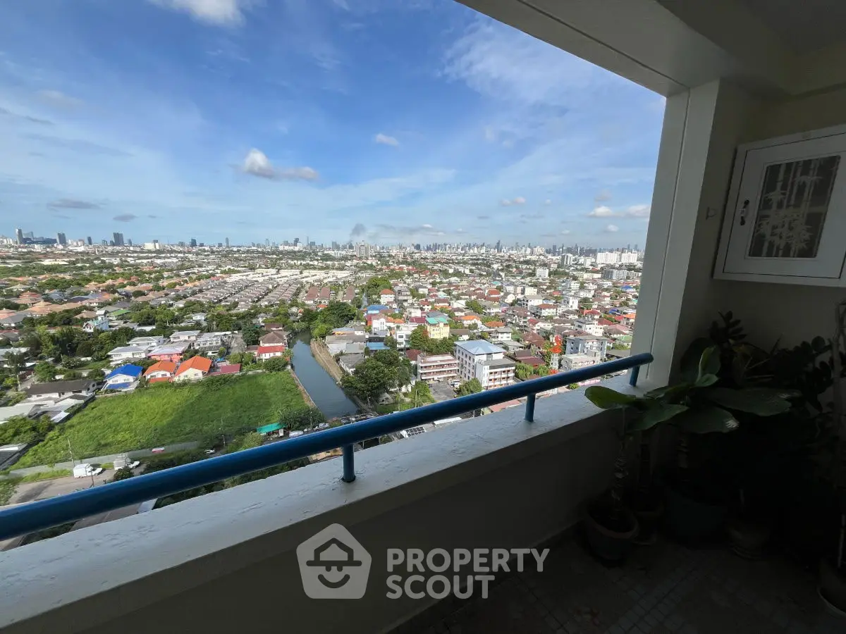 Stunning cityscape view from high-rise balcony with lush greenery and urban skyline.