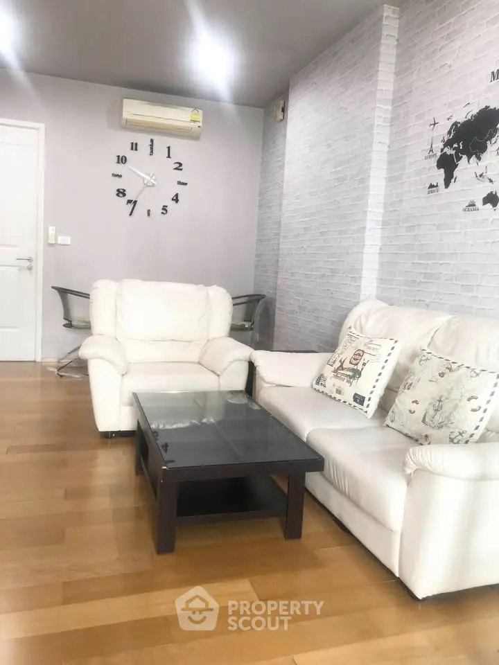 Stylish living room with white sofas, wooden flooring, and modern wall decor in a cozy apartment.