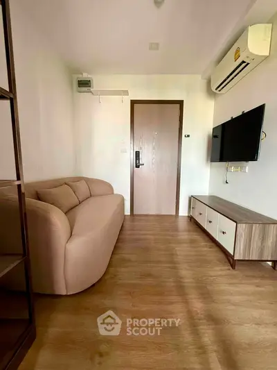 Cozy living room with modern sofa, wall-mounted TV, and wooden flooring in a stylish apartment.