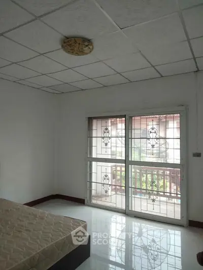 Spacious bedroom with large window and balcony access in a modern apartment.