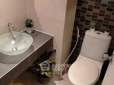 Modern bathroom with stylish glass sink and tiled wall