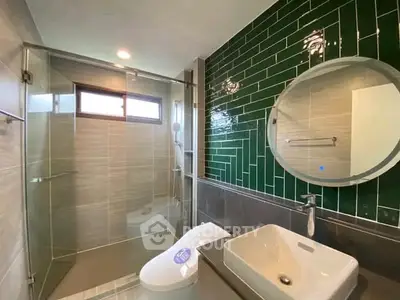 Modern bathroom with glass shower and stylish green tile accent wall