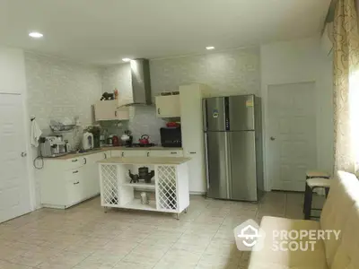 Spacious kitchen with modern appliances and ample counter space, featuring a stylish backsplash and tile flooring, seamlessly opening to a cozy living area.