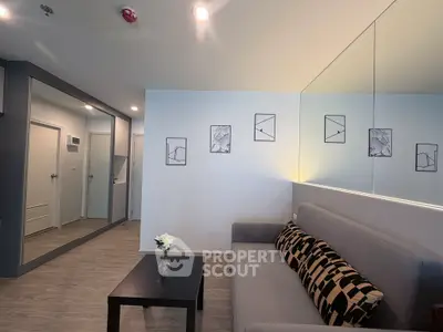 Modern living room with stylish decor and mirrored wall, featuring a cozy sofa and sleek coffee table.