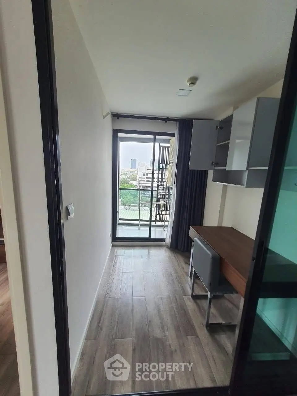 Modern study room with desk and chair, featuring a large window with city view.