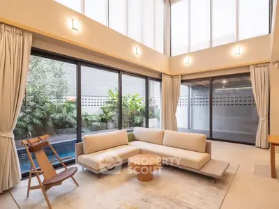 Spacious modern living room with large windows and pool view, perfect for relaxation.