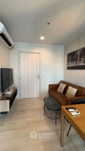 Modern living room with sleek furniture and wall art, featuring a cozy brown sofa and flat-screen TV.