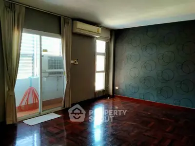 Spacious empty living room with hardwood floors and modern wallpaper